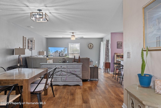 dining area with ceiling fan, hardwood / wood-style floors, and a textured ceiling