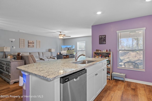 kitchen with white cabinetry, sink, stainless steel dishwasher, a kitchen island with sink, and hardwood / wood-style flooring