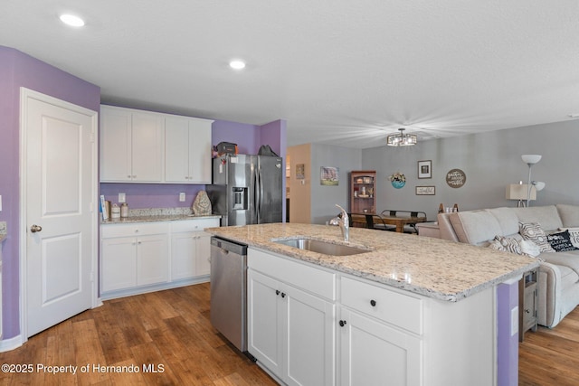 kitchen with white cabinets, an island with sink, stainless steel appliances, and sink