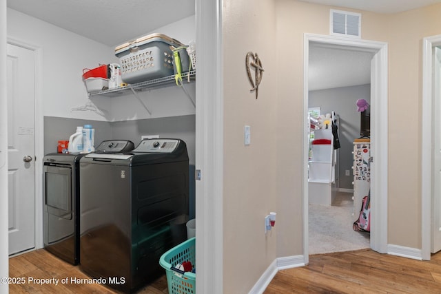 clothes washing area featuring washer and clothes dryer and hardwood / wood-style floors