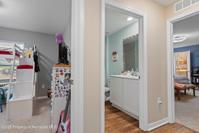 interior space featuring vanity, a textured ceiling, and hardwood / wood-style flooring