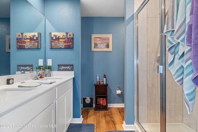 bathroom with hardwood / wood-style floors, vanity, and a shower with shower door