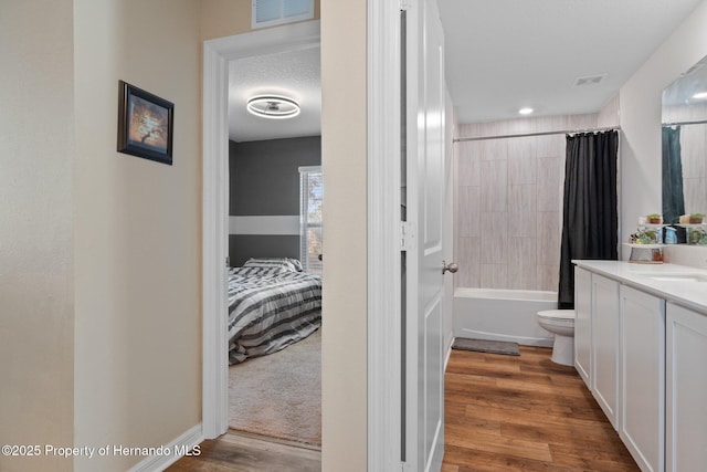 full bathroom with wood-type flooring, a textured ceiling, toilet, shower / tub combo with curtain, and vanity