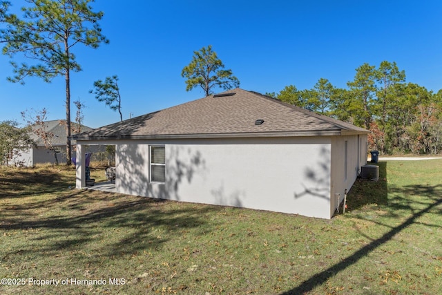 view of side of property with a yard and central AC