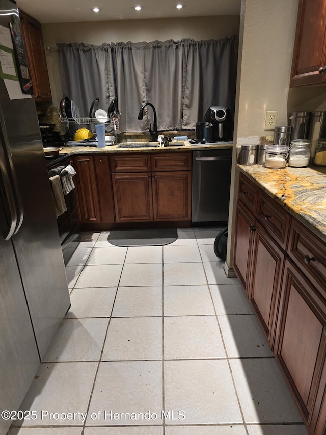 kitchen featuring light stone counters, sink, light tile patterned floors, and stainless steel dishwasher