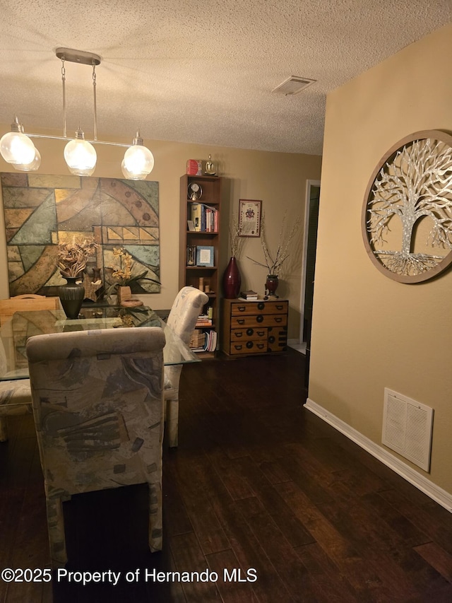 dining room featuring wood-type flooring and a textured ceiling