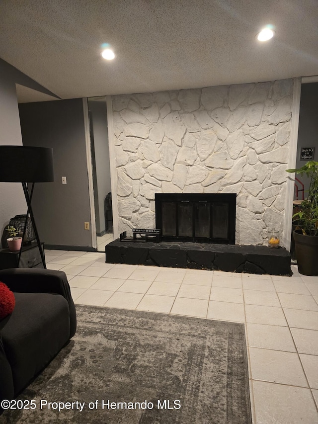 tiled living room featuring a stone fireplace and a textured ceiling