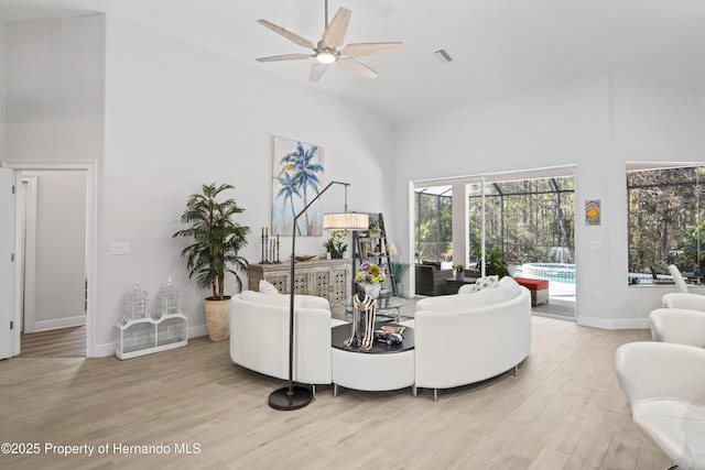 living room with ceiling fan, hardwood / wood-style floors, and high vaulted ceiling