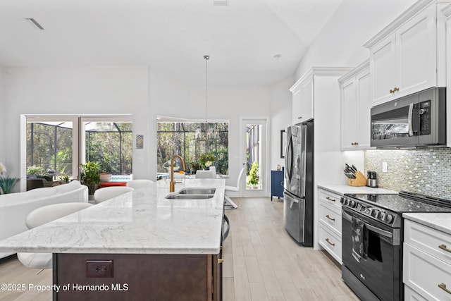 kitchen with white cabinetry, sink, stainless steel appliances, an island with sink, and pendant lighting