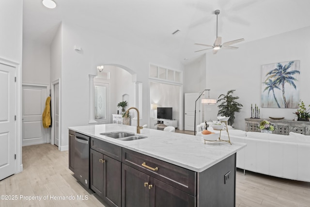 kitchen featuring dark brown cabinetry, ceiling fan, dishwasher, sink, and an island with sink