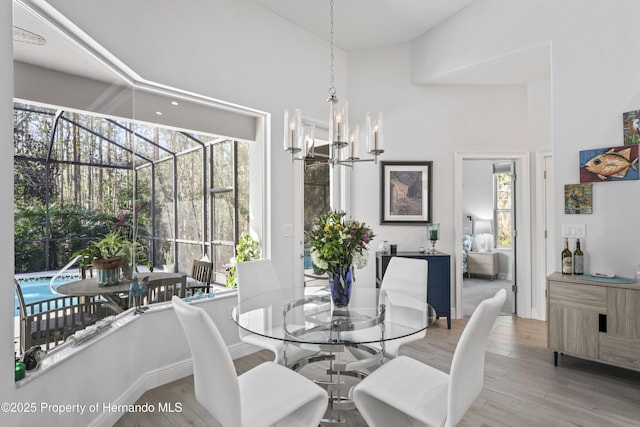 dining space with a high ceiling, hardwood / wood-style flooring, and an inviting chandelier