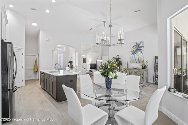 dining room with light hardwood / wood-style floors, sink, and an inviting chandelier