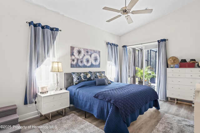 bedroom featuring hardwood / wood-style flooring, ceiling fan, access to exterior, and vaulted ceiling