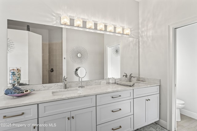 bathroom with a tile shower, vanity, and toilet