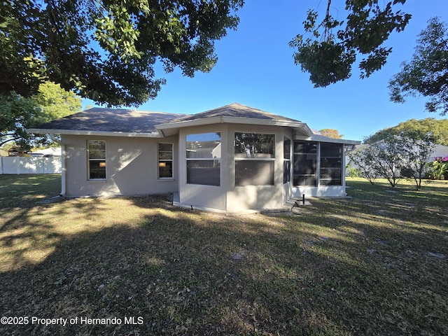 rear view of property with a lawn and a sunroom