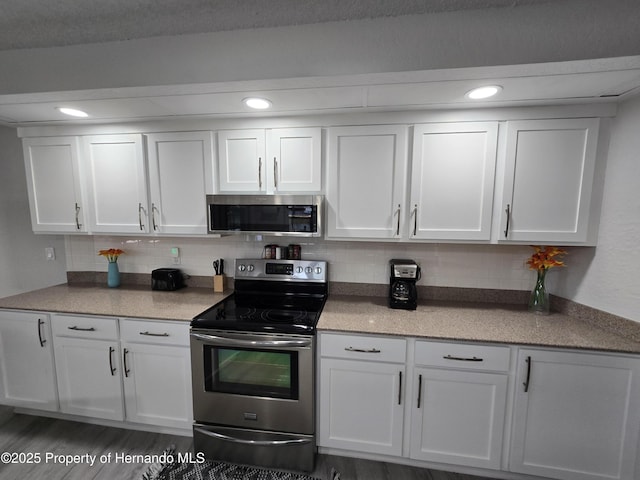 kitchen featuring dark hardwood / wood-style flooring, backsplash, stainless steel appliances, and white cabinetry