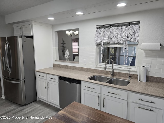 kitchen with decorative backsplash, stainless steel appliances, sink, light hardwood / wood-style flooring, and white cabinetry