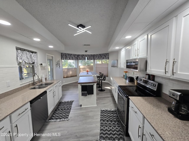 kitchen featuring decorative backsplash, a textured ceiling, stainless steel appliances, sink, and white cabinets