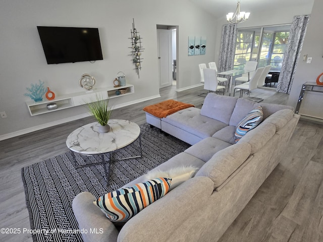 living room featuring an inviting chandelier, wood-type flooring, and vaulted ceiling