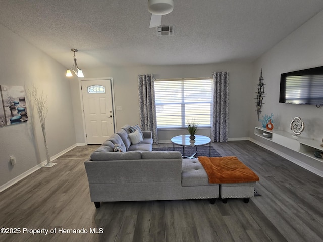 living room with dark hardwood / wood-style flooring, a textured ceiling, and an inviting chandelier