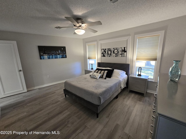 bedroom with ceiling fan, dark wood-type flooring, and a textured ceiling