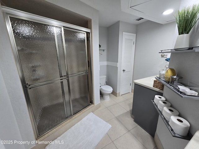 bathroom with tile patterned flooring, toilet, and a shower with shower door