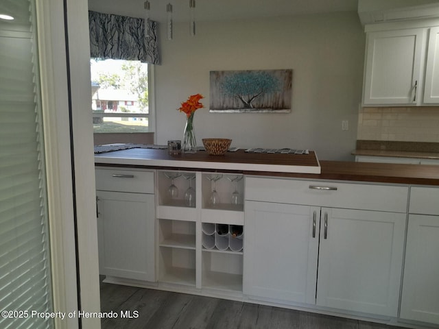 kitchen featuring decorative backsplash, dark hardwood / wood-style flooring, white cabinetry, and butcher block counters