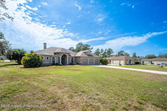 view of front of house with concrete driveway, a chimney, an attached garage, and a front yard