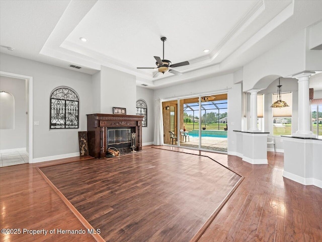 unfurnished living room with dark wood-style floors, decorative columns, a raised ceiling, visible vents, and baseboards