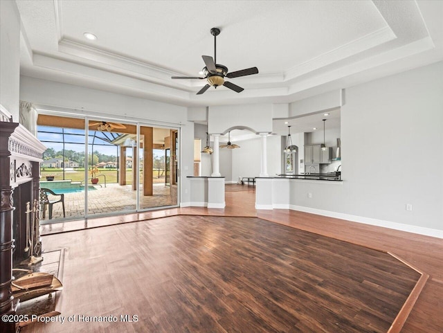 unfurnished living room featuring a tray ceiling and wood finished floors