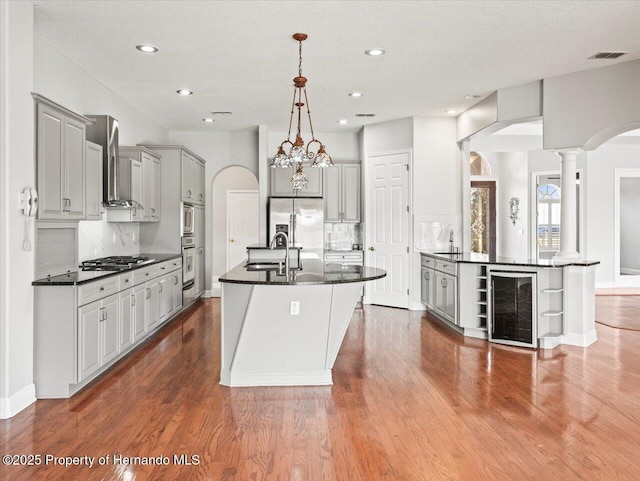 kitchen featuring an island with sink, wine cooler, and gray cabinets