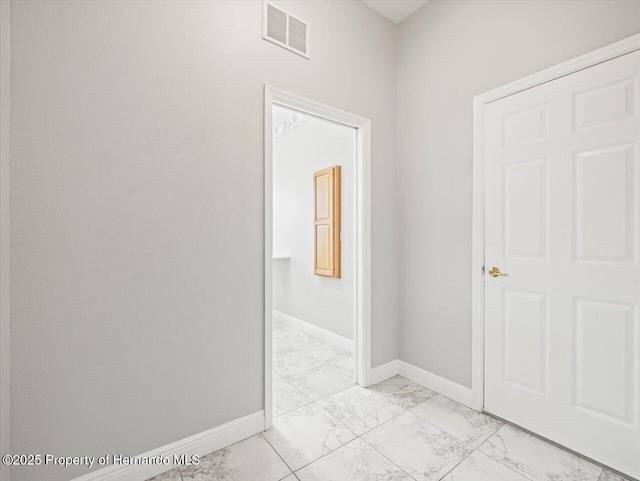 hallway with marble finish floor, visible vents, and baseboards