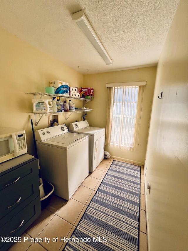 laundry room featuring independent washer and dryer, a textured ceiling, and light tile patterned floors