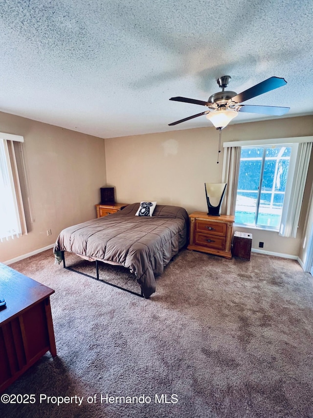 carpeted bedroom with ceiling fan and a textured ceiling