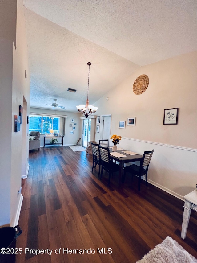 dining area featuring ceiling fan with notable chandelier, dark hardwood / wood-style floors, a textured ceiling, and vaulted ceiling