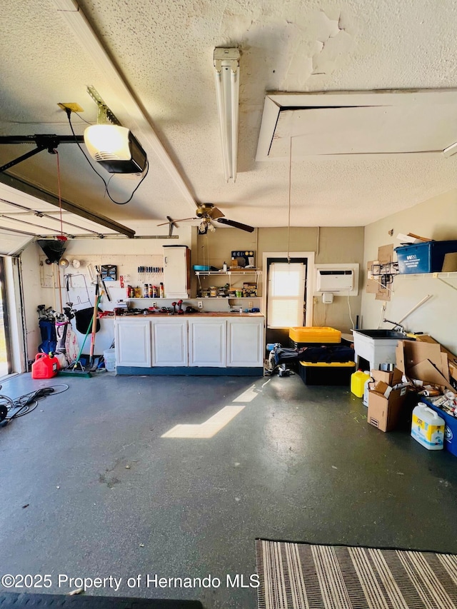 garage featuring a workshop area, a garage door opener, a wall mounted AC, and ceiling fan