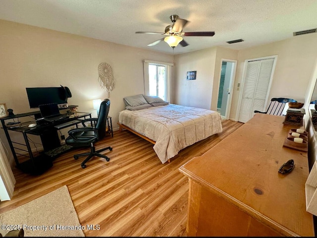 bedroom with a closet, a textured ceiling, light hardwood / wood-style floors, and ceiling fan