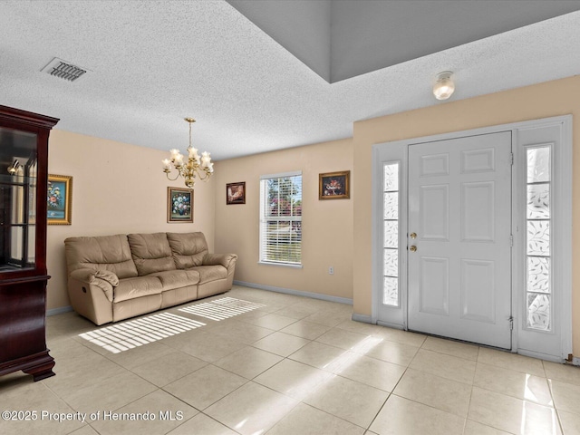 tiled foyer with a chandelier and a textured ceiling