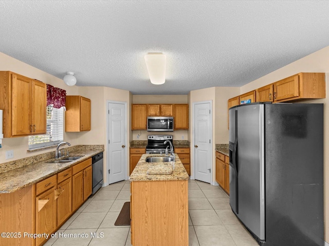 kitchen with a center island with sink, light tile patterned floors, stainless steel appliances, and sink