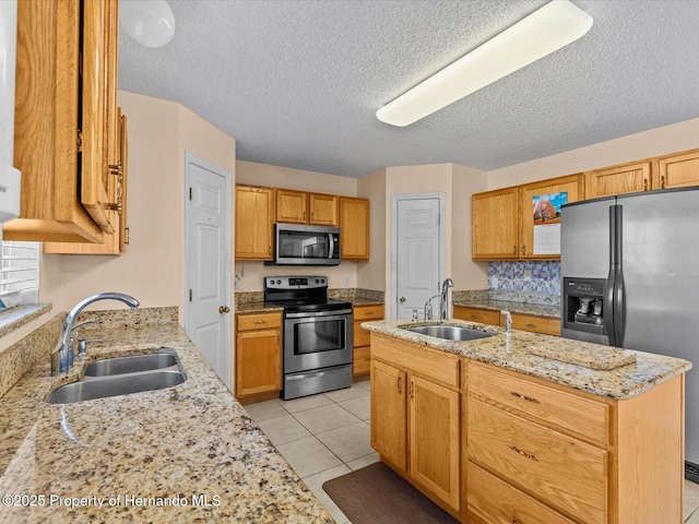 kitchen with a kitchen island with sink, sink, light tile patterned flooring, and stainless steel appliances