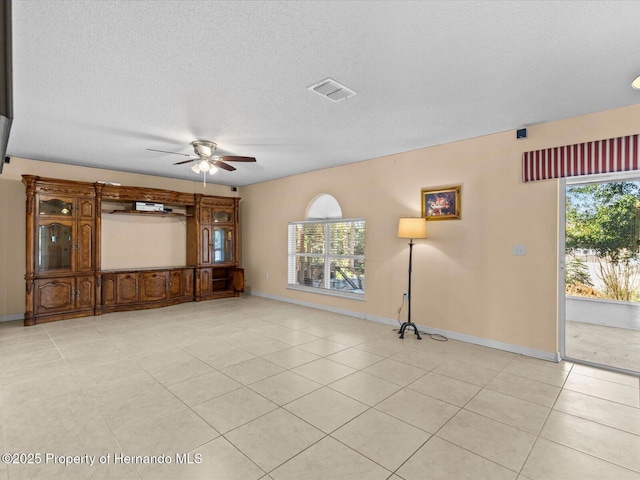 unfurnished living room with light tile patterned flooring, a textured ceiling, a wealth of natural light, and ceiling fan