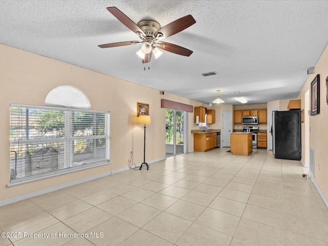 unfurnished living room with ceiling fan, light tile patterned floors, and a textured ceiling