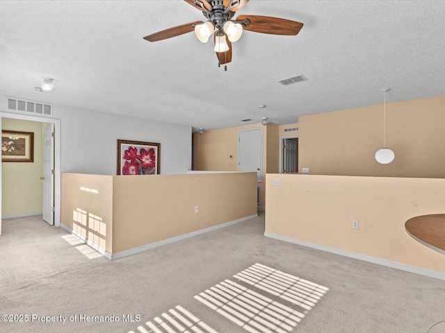 spare room with ceiling fan, light colored carpet, and a textured ceiling