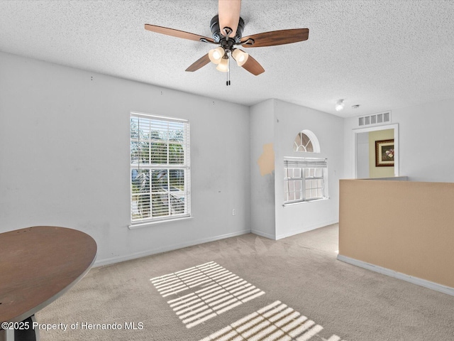 unfurnished living room featuring light carpet, a textured ceiling, and ceiling fan