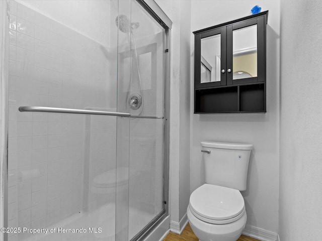 bathroom featuring toilet and a shower with door