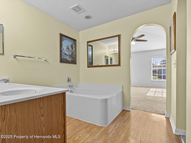 bathroom featuring hardwood / wood-style floors, vanity, a bathing tub, and a textured ceiling