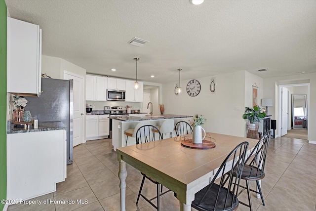 dining area featuring sink, light tile patterned flooring, and a textured ceiling