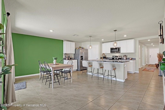 dining space with sink, light tile patterned floors, and a textured ceiling