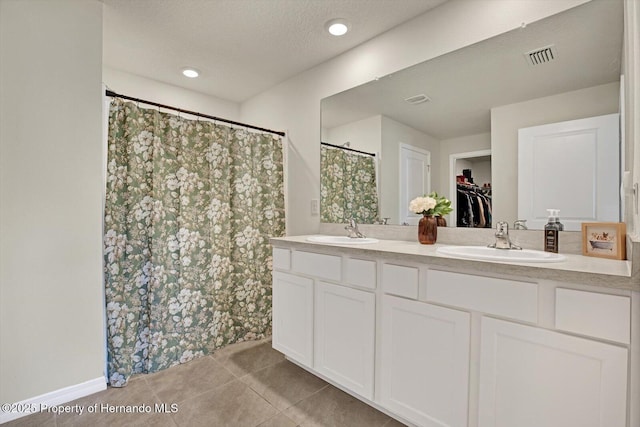 bathroom with tile patterned floors, curtained shower, vanity, and a textured ceiling