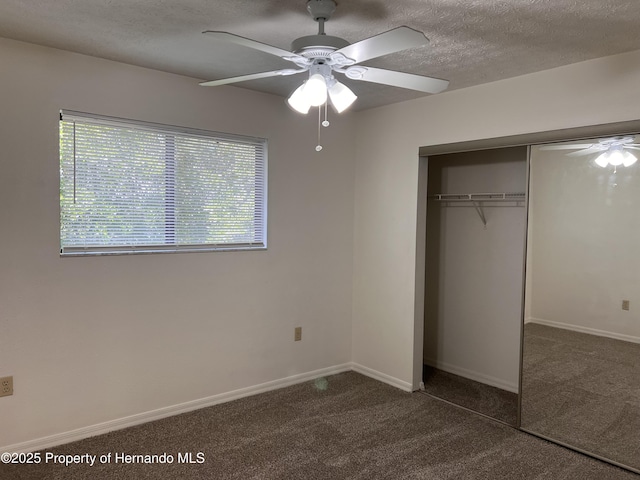 unfurnished bedroom featuring a textured ceiling, a closet, ceiling fan, and dark colored carpet